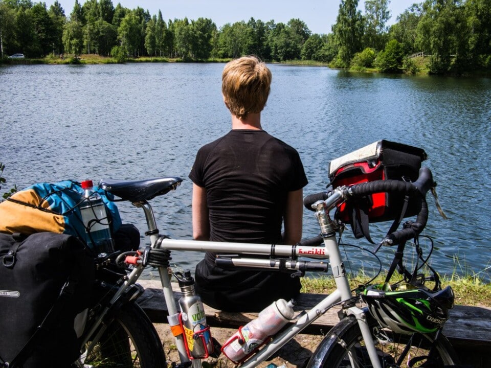 jane sitting by a lake in latvia with her bike